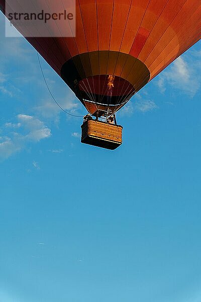 Heißluftballon im Flug mit unerkennbaren Menschen im Inneren an einem Tag mit blauem Himmel