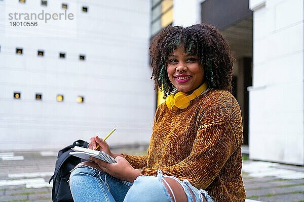 Porträt eines schwarzen ethnischen Mädchens  das im College sitzt und Klassenarbeiten erledigt oder für eine Prüfung lernt