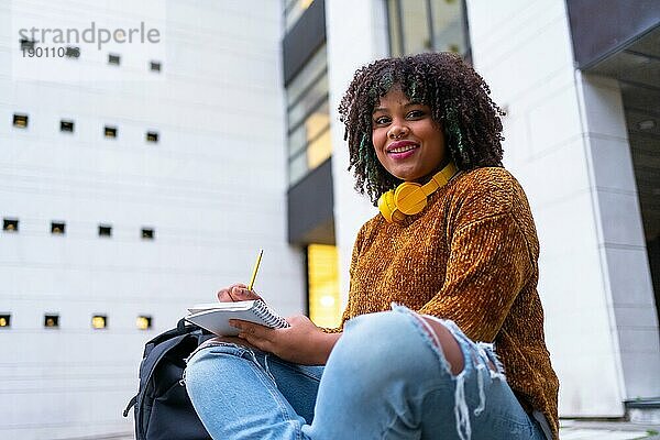 Porträt eines schwarzen ethnischen Mädchens  das im College sitzt und Klassenarbeiten erledigt oder für eine Prüfung lernt