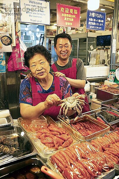 Koreanische Frau und Koreanischer Mann mit einer Krabbe  Gwangjang Markt  traditioneller Straßenmarkt in Jongno-gu  Seoul  Südkorea  Asien