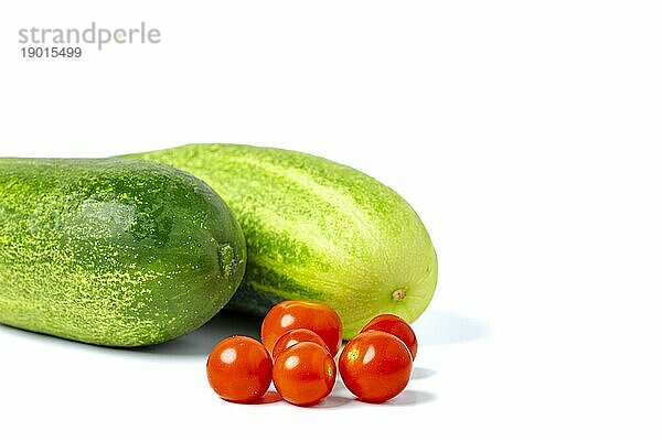 Feldgurken (Cucumis sativus) und Cocktailtomaten (Solanum lycopersicum)  auf weiß  Kopierraum