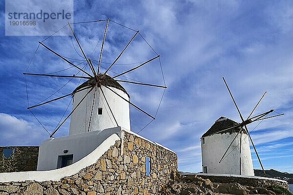 Berühmte Touristenattraktion von Mykonos  Kykladen  Griechenland. Zwei traditionelle  weiß getünchte Windmühlen am Wasser und in der Stadt Chora. Sommer  blauer Himmel  schöne Wolken. Reiseziel  ikonische Ansicht. Frontalaufnahme