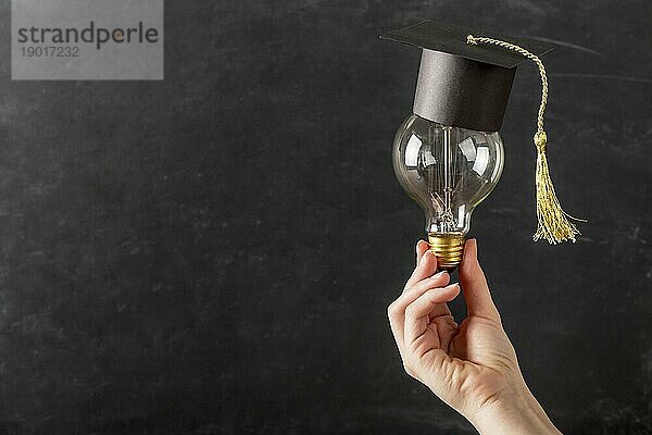 Person hält Glühbirne mit Graduierungskappe. Auflösung und hohe Qualität schönes Foto