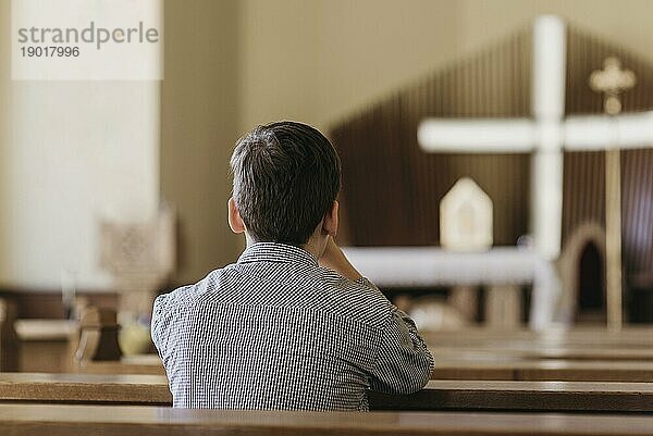 Rückansicht Junge betet in der Kirche. Foto mit hoher Auflösung