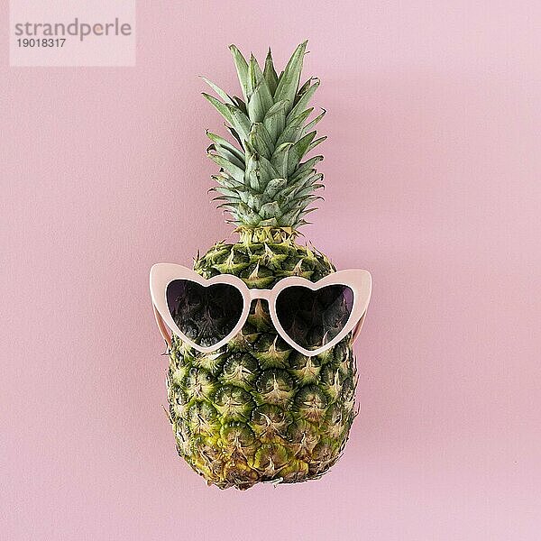 Draufsicht Ananas mit herzförmiger Sonnenbrille. Schönes Foto