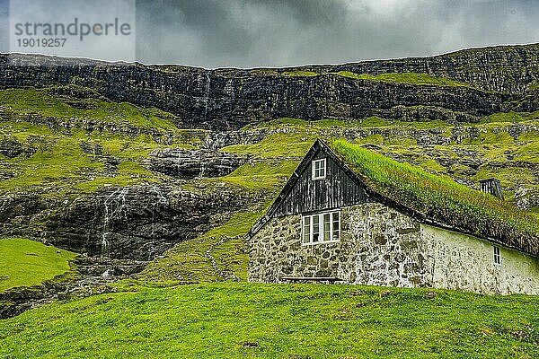 Haus mit Reetdach vor einem Wasserfall  Saksun  Streymoy  Färöer Inseln  Dänemark  Europa