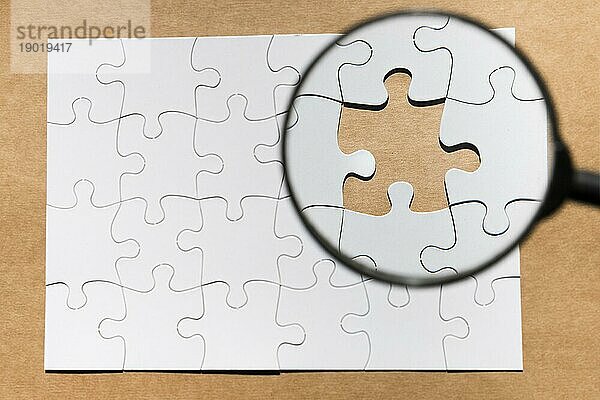 Lupe fehlt Puzzle braunem Papier strukturierten Hintergrund