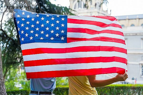 Ehepaar in der Stadt mit usa Flagge  Junge und Mädchen auf dem Rücken. Patrioten stolz auf ihre Nation  Unabhängigkeitstag