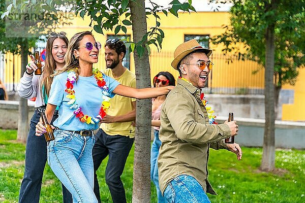 Gruppe multiethnischer Freunde auf einer Geburtstagsfeier im Stadtpark  die tanzen  Partykleidung tragen und im Sommer Sonnenbrillen tragen