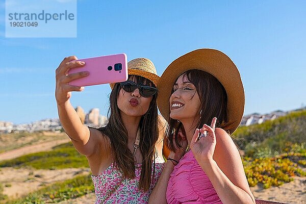 Frau Freunde mit Hut im Urlaub am Strand nehmen ein Selfie mit dem Telefon lächelnd