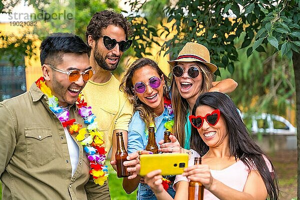 Multiethnische Gruppe von Freunden  die im Stadtpark feiern und ein Selfie machen  lächelnd beim Betrachten der Fotos auf dem Handy