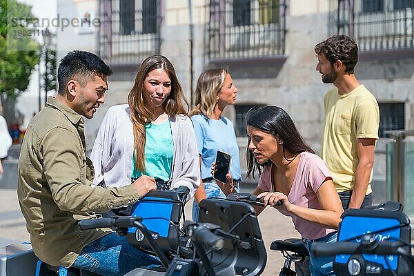 Eine Gruppe multiethnischer Freunde in der Stadt  die Fahrräder mieten und mit der Handy App Spaß haben