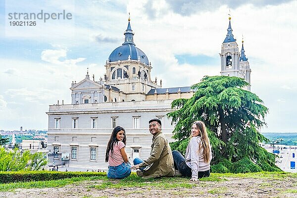 Porträt von Touristenfreunden  die die Stadt Madrid im Sommerurlaub besuchen. Sitzen mit Blick auf die Almudena