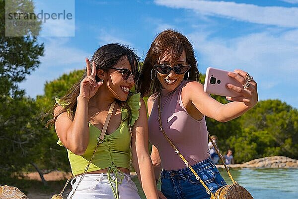 Kaukasische Freundinnen machen ein Selfie mit dem Handy im Sommerurlaub in einem Park