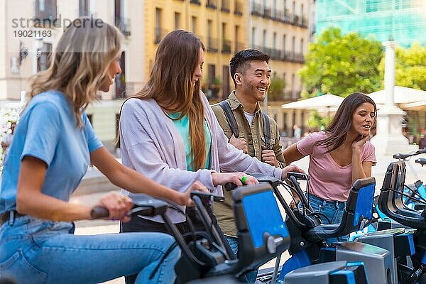 Gruppenbild von multiethnischen Freunden in der Stadt neben Leihfahrrädern  die Spaß haben
