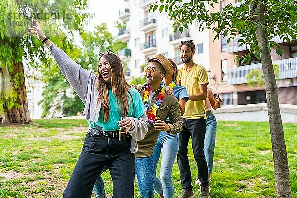 Eine Gruppe multiethnischer Freunde tanzt auf einer Geburtstagsfeier im Stadtpark