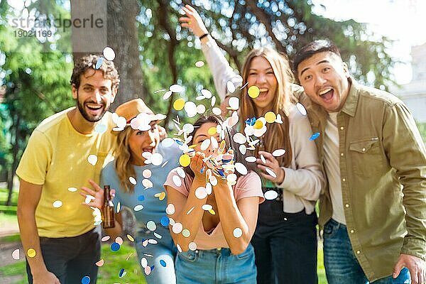 Portrait multiethnische Gruppe von feiernden werfen Konfetti lächelnd im Park  Spaß mit Freunden Konzept