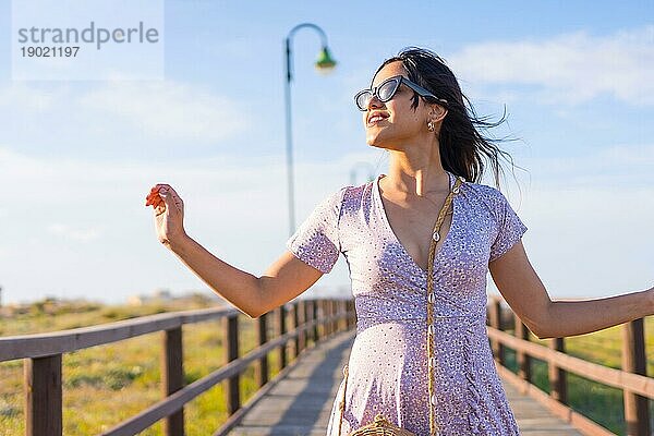 Porträt der kaukasischen brunette Frau lächelnd auf Sommerferien neben dem Strand Sand auf einem Gehweg