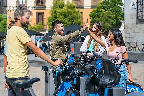 Gruppe multiethnischer Freunde in der Stadt neben Leihfahrrädern lächelnd