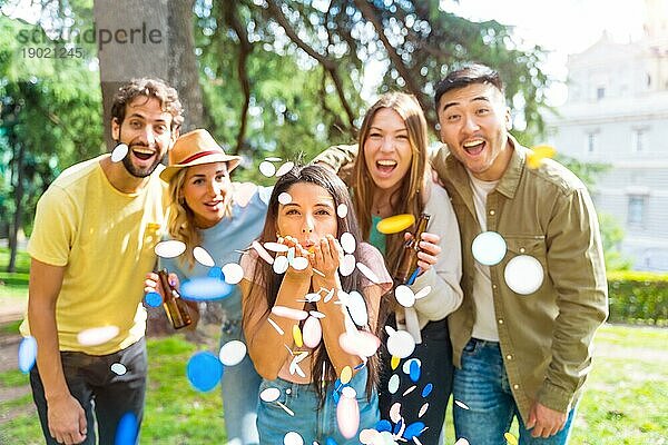 Portrait multiethnische Gruppe von feiernden werfen Konfetti lächelnd im Park  Spaß mit Freunden Konzept