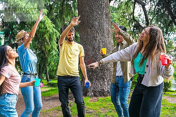 Eine multiethnische Gruppe von Geburtstagsgästen im Stadtpark hat viel Spaß beim Tanzen zu Musik