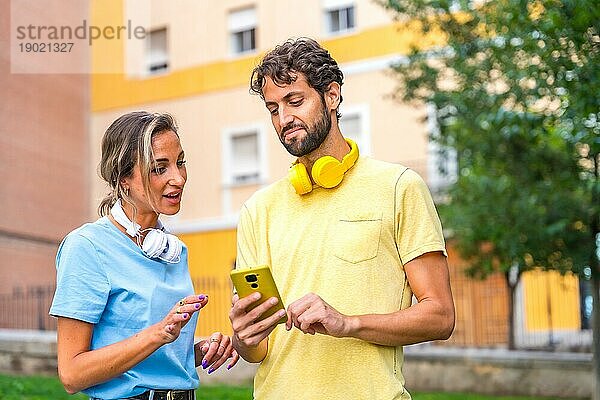 Erwachsenes Paar verwendet Smartphone zusammen in der Stadt Straße neben dem Park