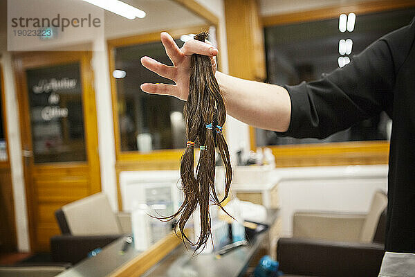 Ein junges Mädchen spendet Haare an ihren Friseur  einen Partner eines Vereins  der Krebspatienten Perücken vertreibt.