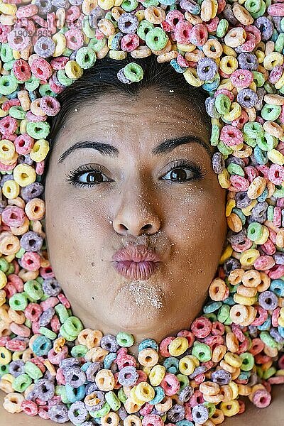 Ein wunderschönes junges hispanisches Model ist mit Frühstücksflocken bedeckt und zeigt nur ihr Gesicht