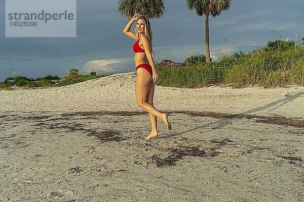 Ein schönes blondes Bikinimodell genießt das Wetter draußen am Strand