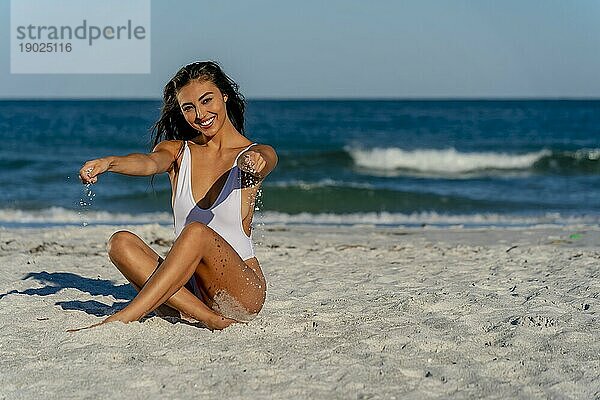 Ein wunderschönes Mixed race Bikinimodell genießt das Wetter draußen am Strand