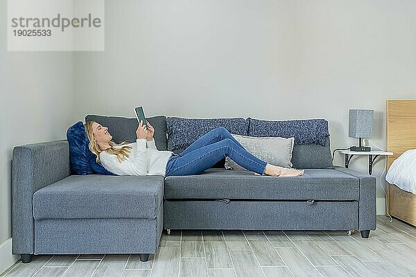 Schöne junge Frau  die ihre Zeit zu Hause beim Lesen eines Romans genießt