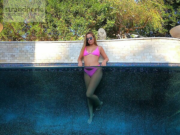Ein junges wunderschönes brünettes Modell genießt einen Tag am Pool