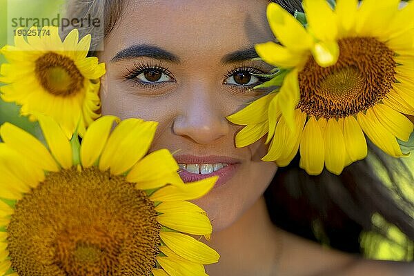 Eine schöne asiatische Brunette Modell posiert im Freien in einem Feld von Sonnenblumen