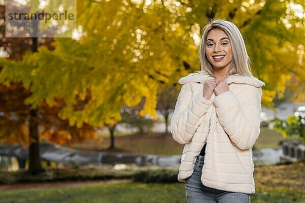 Ein wunderschönes junges blondes Modell posiert im Freien und genießt einen Herbsttag