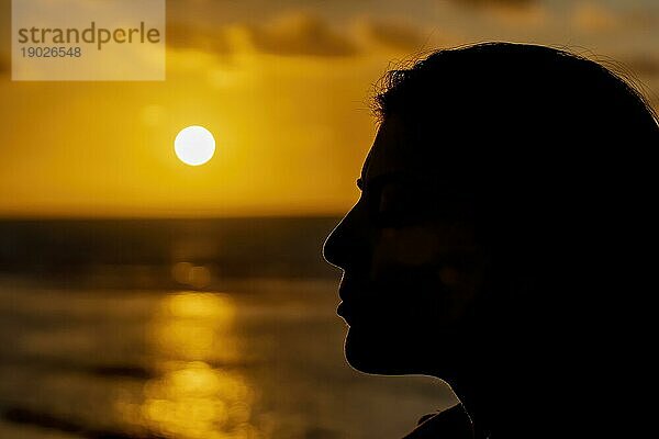 Die Silhouette einer Frau  die den Sonnenuntergang über dem Mittelmeer in Marokko beobachtet