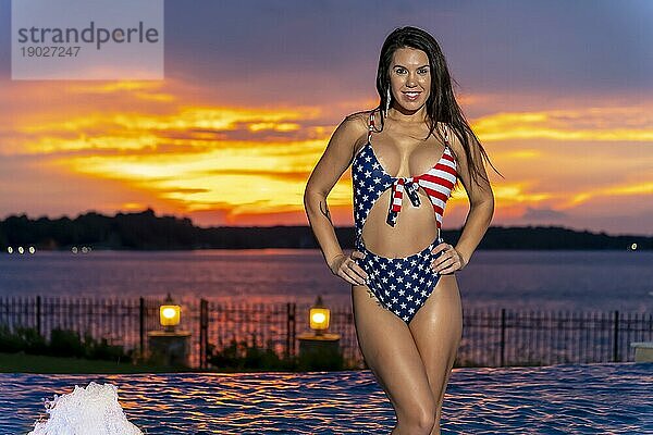 Porträt einer Frau  die einen patriotischen amerikanischen Bikini trägt  während sie einen Sonnenuntergang in einer Sommernacht genießt