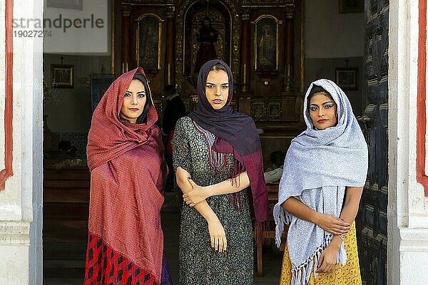 Drei wunderschöne hispanische  brünette Modelle posieren im Freien in einer katholischen Kirche