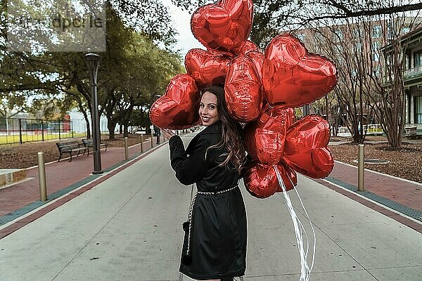 Eine schöne Brünette Modell mit einem Dutzend Luftballons für Valentinstag