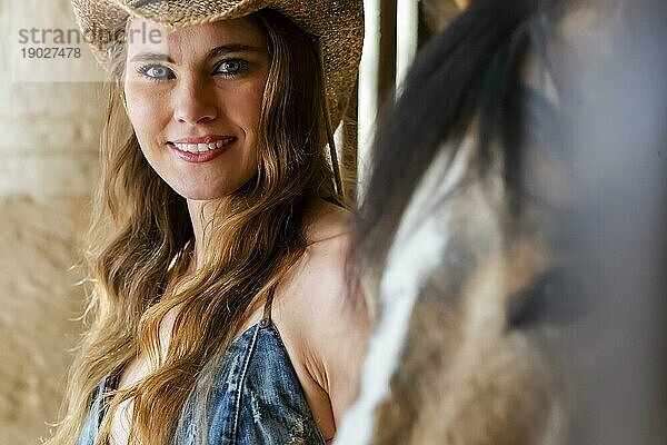 Ein wunderschönes Hispanic Brunette Modell posiert mit einem Pferd im Freien in einem mexikanischen Stall