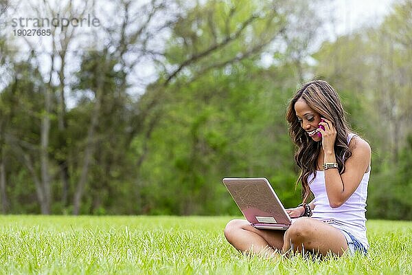 Eine junge afroamerikanische Frau arbeitet an ihrem Laptop und genießt einen Tag im Park