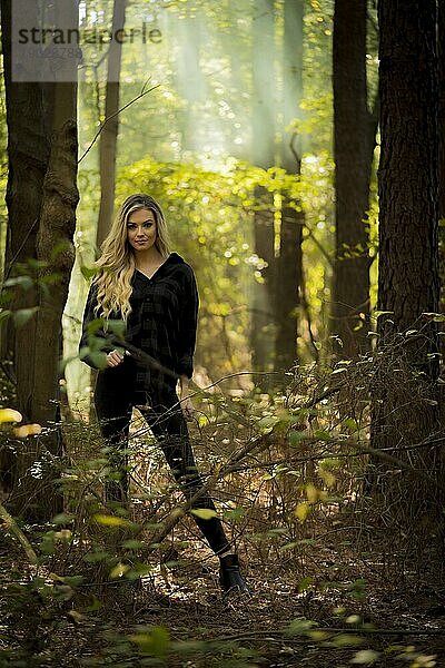 Ein wunderschönes blondes Modell posiert im Freien in einer stimmungsvollen Waldumgebung