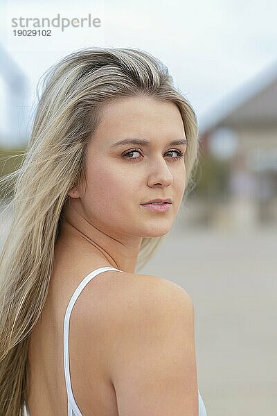 Ein wunderschönes junges blondes Model genießt einen Sommertag mit ihrem Skateboard