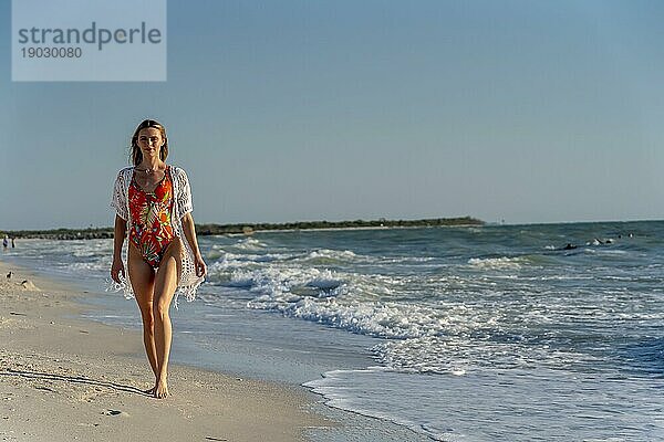Ein schönes brünettes Bikinimodell genießt das Wetter draußen am Strand