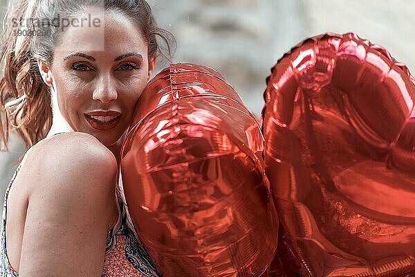 Eine schöne Brünette Modell mit einem Dutzend Luftballons für Valentinstag