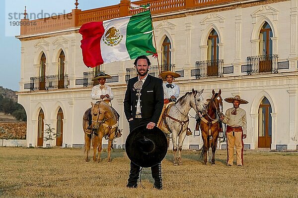 Ein stattlicher mexikanischer Charro posiert vor einer Hazienda in der mexikanischen Landschaft