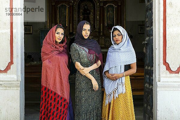 Drei wunderschöne hispanische  brünette Modelle posieren im Freien in einer katholischen Kirche