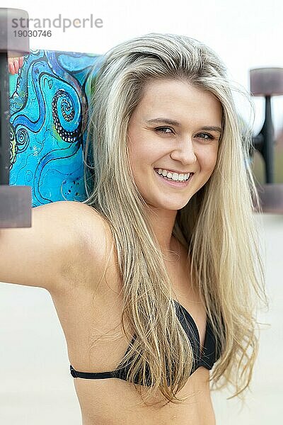 Ein wunderschönes junges blondes Model genießt einen Sommertag mit ihrem Skateboard