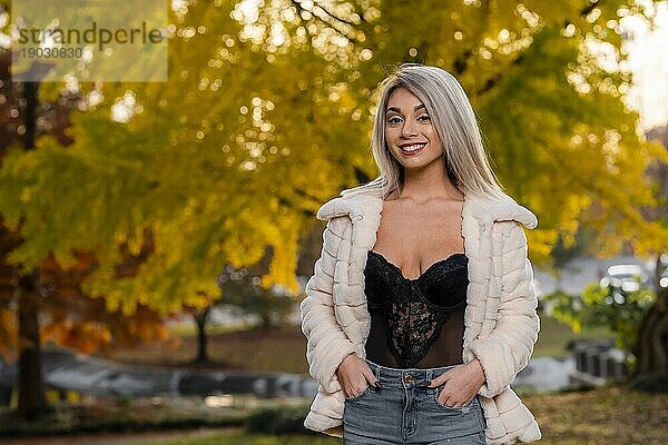 Ein wunderschönes junges blondes Modell posiert im Freien und genießt einen Herbsttag