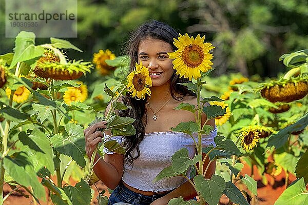Eine schöne asiatische Brunette Modell posiert im Freien in einem Feld von Sonnenblumen