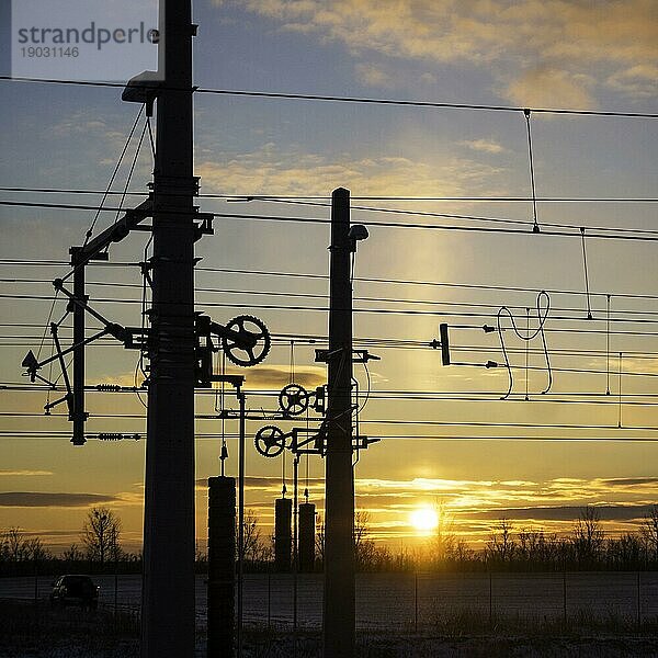Eisenbahnmast und Kabel bei Sonnenaufgang